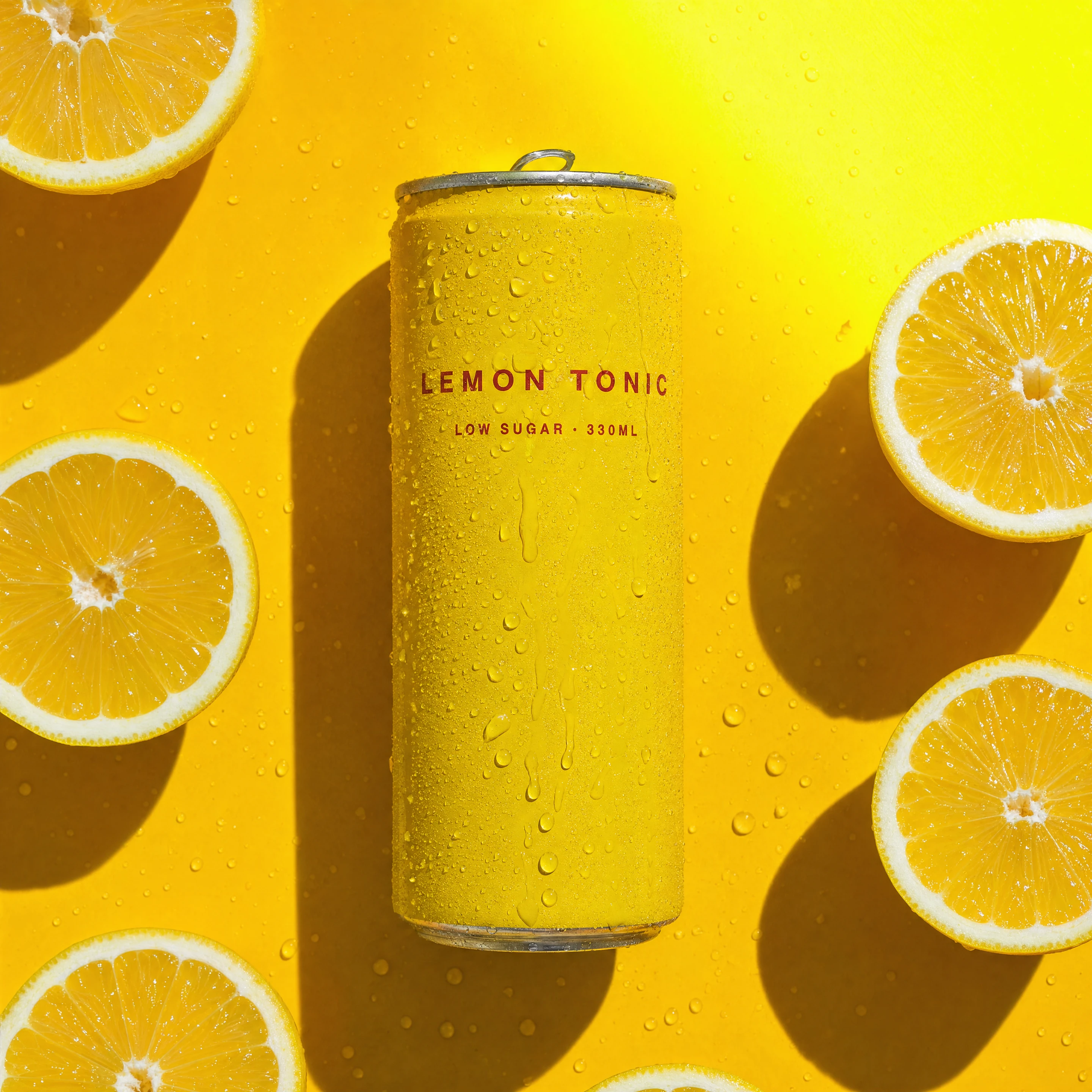 Dew-covered lemon tonic can with lemon slices on a bright yellow background.
