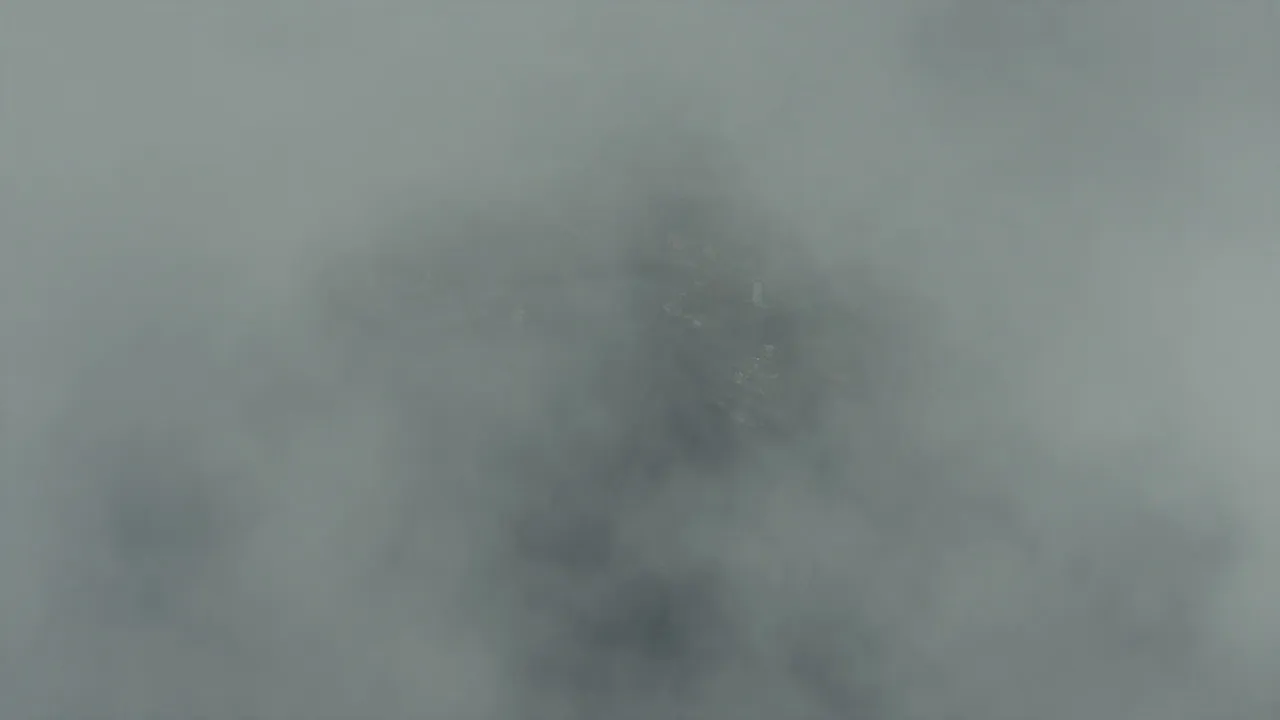 30-second cosmic horror movie trailer, 1990s theatrical style, complete with title cards. Character A: a marine biologist in her 40s, salt-crusted parka, chapped face, deep exhaustion in her eyes. Character B: an old harbor master in his 70s, milky left eye, oilskin coat, trembling hands. Setting: a decaying fishing village on a black ocean, thick fog, crooked docks, a dead lighthouse. Structure: Cold open (0-4s): slow aerial descent through fog toward the village, the ocean unnaturally still, a vast dark shape suggested beneath the surface; low drone building. Beat one (4-9s): quick cuts, abandoned boats, nets dropped mid-haul, a meal still steaming on a crate, the biologist walking the empty dock; whispered voice-over tone. Title card (9-11s): black screen, white serif text: 'THIS SUMMER'. Beat two (11-17s): the harbor master grabs her arm and points at the water; the tide pulls back too far, too fast, exposing monolithic carved stones that should not exist; thousands of seabirds flee inland. Title card (17-19s): black screen: 'SOME THINGS SLEEP'. Beat three (19-25s): accelerating montage, the fog glowing sickly green from below, villagers running, the lighthouse flickering back to life on its own, the biologist screaming something we cannot hear, waves rising; music swelling then cutting to silence. Final card (25-28s): title reveal in weathered serif letters: 'THE DEEP BELOW', text slowly warping as if underwater. Stinger (28-30s): one last shot, the ocean surface, calm, then a colossal eye opens just beneath it; hard cut to black with a deep boom. Trailer editing grammar: rhythmic cuts synced to sound design, dread through suggestion, the creature never fully shown until the final stinger. Desaturated cold palette with sickly green undertones, heavy fog diffusion, 35mm film grain, deep sub-bass rumble, distant foghorn.